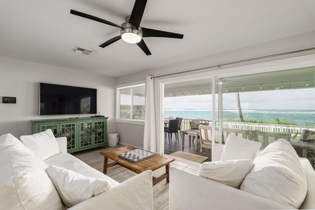 Sink into plush white sofas while ocean waves dance beyond your private balcony, where coastal breezes flow through sliding doors.