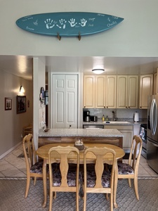 Gather around this welcoming kitchen and dining area, where family memories come to life. The spacious granite counters and stainless appliances make meal prep easy, while the surfboard decor adds coastal charm.