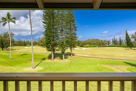 Scenic golf course view featuring lush fairways, mature trees, and tropical palms under a bright blue sky—visible from the property's private balcony.