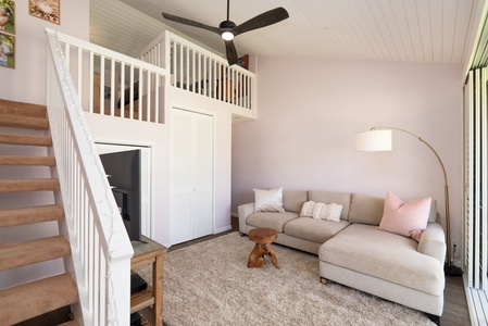 Relax on your plush sectional beneath soaring ceilings, where a cozy loft adds charm and your private retreat awaits upstairs.
