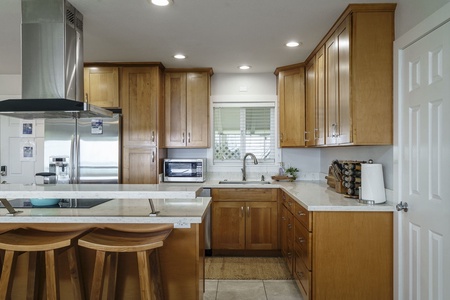 Your fully-equipped kitchen awaits with warm wood cabinets, granite countertops, and modern appliances for creating memorable meals together.