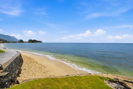 Coastal property with direct beach access on pristine golden sands, framed by mountains and azure waters under clear tropical skies.
