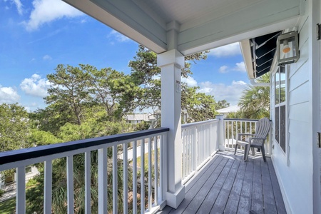 Sip your morning coffee from this peaceful balcony, where you can soak in lush tree-lined views and feel the gentle coastal breeze beneath a covered porch.
