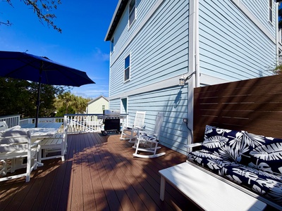 Relax on your private deck with stylish seating, rocking chairs, and BBQ grill under sunny skies.