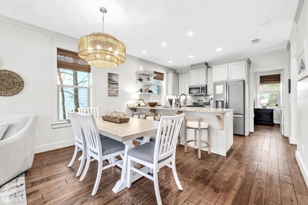 Your open-plan kitchen flows seamlessly into the dining area, where coastal charm meets modern comfort under warm pendant lighting.
