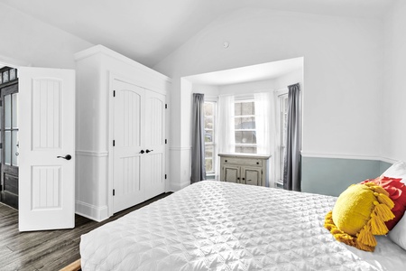 Relax in this bright, airy bedroom with its crisp white linens, colorful accent pillows, and charming built-in storage.