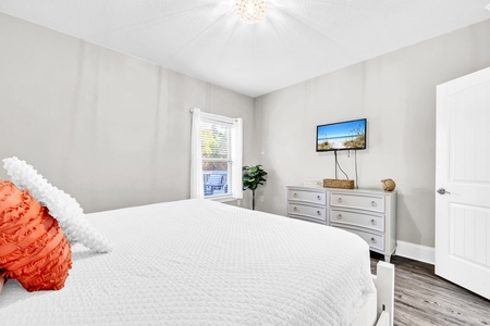 Relax in your peaceful bedroom featuring crisp white linens, modern furnishings, and entertainment at your fingertips.