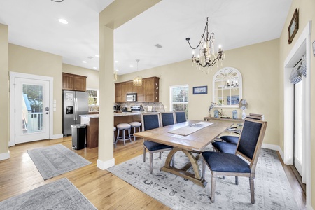 Step into your open-concept dining and kitchen area, where a stunning chandelier sets the tone for memorable meals. Natural light pours through windows, highlighting warm wood floors and elegant finishes—perfect for gathering with loved ones.