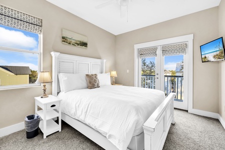The 2nd floor queen bedroom with crisp linens, charming beach decor, and French doors opening to the balcony.