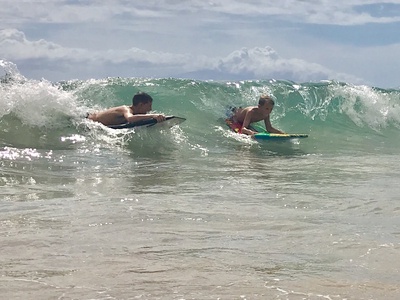 Beach area features perfect waves for bodyboarding and water activities during sunny summer days.
