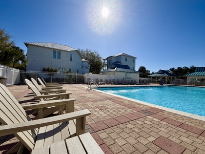 Sparkling community pool surrounded by comfortable lounge chairs under bright Florida sunshine, perfect for relaxing afternoons.
