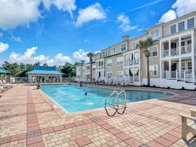 Featuring a sparkling swimming pool surrounded by coastal architecture and palm trees under sunny skies.