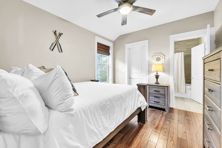 Sink into crisp white linens in your serene bedroom, where warm wood floors and a gentle ceiling fan create the perfect retreat.