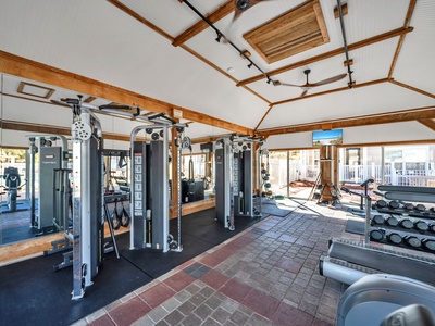 Your fitness routine continues in this well-equipped gym featuring modern equipment and natural light streaming through large windows.