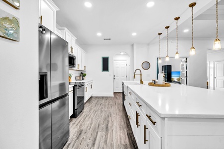 Your modern kitchen sparkles with white cabinets, granite counters, and pendant lights, perfectly equipped for memorable meals together.