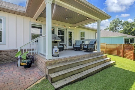 A covered patio with outdoor seating and string lights creates the perfect spot to unwind, complete with a grill for sunny afternoon cookouts.