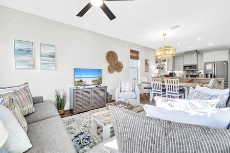 Relax in your coastal-inspired living space with plush seating, beach artwork, and open kitchen - perfect for unwinding after beach days.
