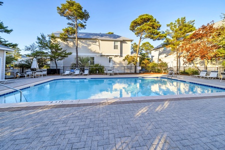 Sparkling community pool surrounded by mature trees and comfortable lounge chairs, perfect for relaxing sunny afternoons.