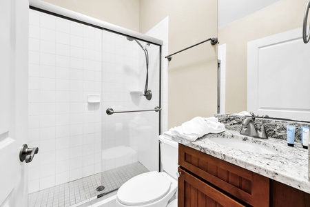 The ground floor full-bathroom features a spacious walk-in shower, granite countertops, and thoughtful amenities for your comfort.
