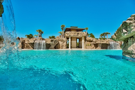 The spectacular lagoon-style pool with dramatic waterfalls under brilliant blue skies.