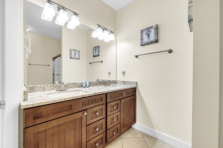 Freshen up at your spacious double vanity with gleaming granite countertops and warm wood cabinetry. Bright lighting and a large mirror make every morning feel effortless.