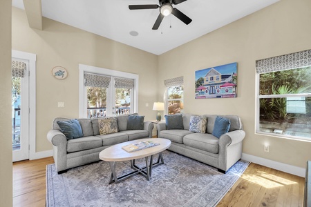 Sink into plush sofas and unwind in your sunlit living room, where coastal breezes flow through open windows and a ceiling fan keeps you cool. Perfect for lazy afternoons or lively game nights with loved ones.