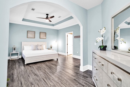 Unwind in this serene master suite with its soothing coastal blue walls, elegant tray ceiling, and luxurious hardwood floors that create your perfect peaceful retreat.