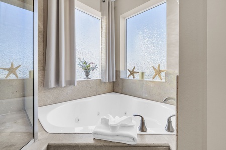 Soak in your private soaking tub surrounded by ocean-inspired decor and natural light streaming through corner windows.