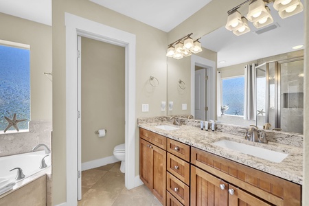 Your bathroom features dual vanities with granite countertops and warm wood cabinetry, creating a spacious retreat where morning routines feel luxurious and easy.