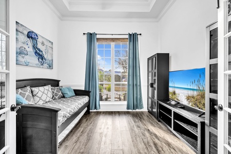 Your coastal-themed bedroom features ocean artwork, a comfortable bed, and large TV for perfect relaxation after beach days.