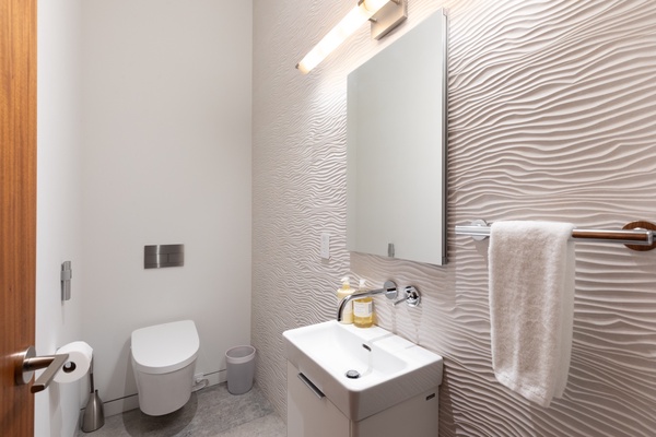 Stylishly appointed with high-end wall treatment and fixtures, this powder room is ideally situated by the Media Room and the kitchen.