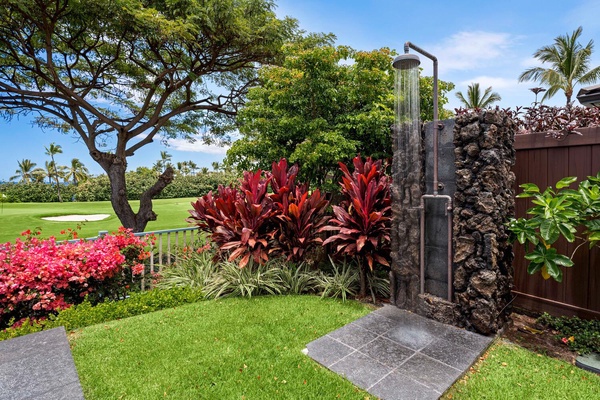 Outdoor shower surrounded by lush plants and a view of the golf course.