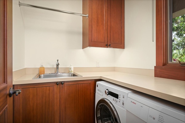 Fully equipped laundry room with washer, dryer, sink and counter space.