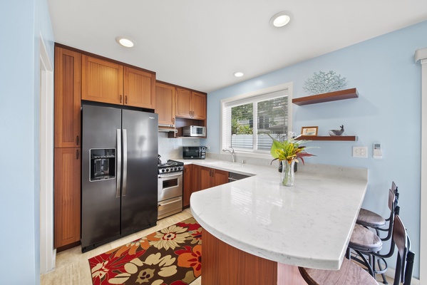 Inside the French doors you walk into a full kitchen with an apartment sized stove and refrigerator, custom cabinetry, and stone countertops