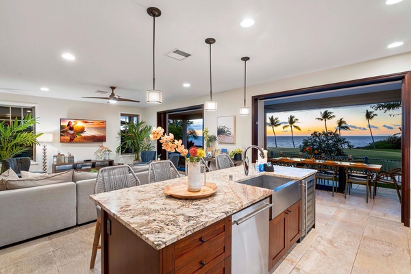 Modern kitchen with an island and a view of the sunset over the ocean.