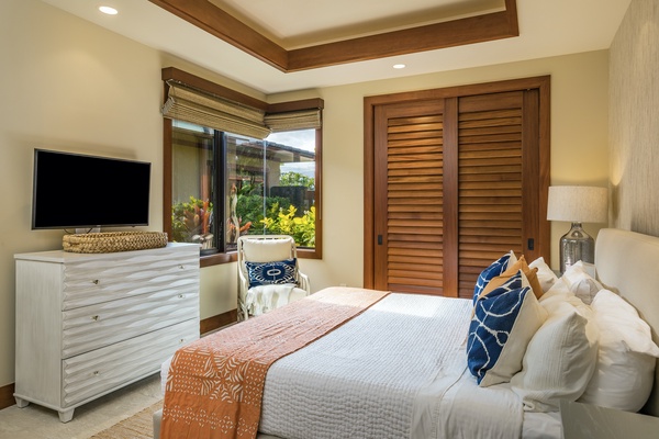 Guest bedroom one, off the great room, has a large cornerless window that frames the beautiful garden courtyard.