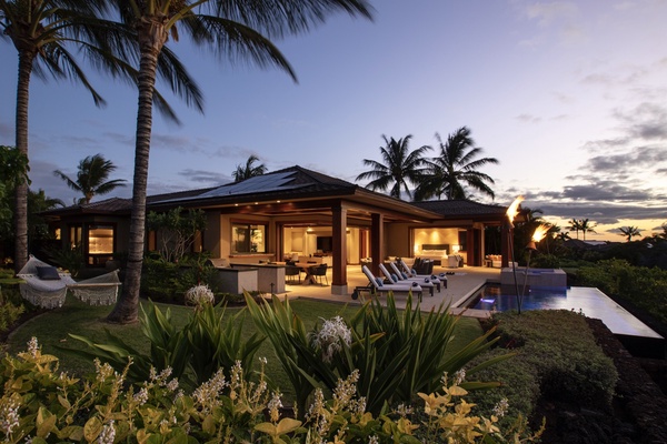 Pool deck with tiki torches aflame as sunset turns to twilight.