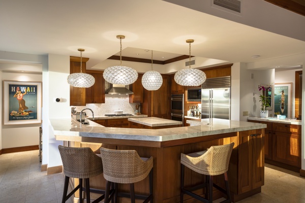 Alternate view of the kitchen, fully equipped with top-tier appliances, ample prep space & bar seating