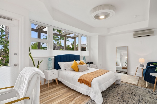 Step into the serene Primary Suite with gleaming hardwood floors leading towards a cozy bed, framed by a stylish blue headboard.