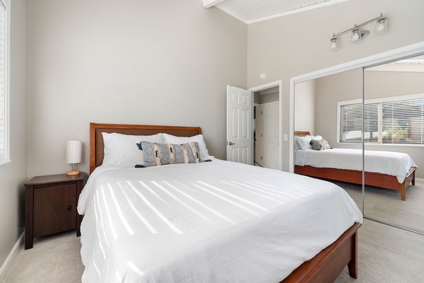 Bright and airy second guest bedroom with a comfortable bed and mirrored closet doors.