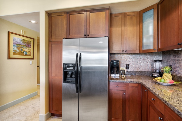 The fully equipped gourmet kitchen with stainless steel appliances, granite countertops, and bar seating flows seamlessly into a dining area for six and a welcoming living space with ample comfortable seating.