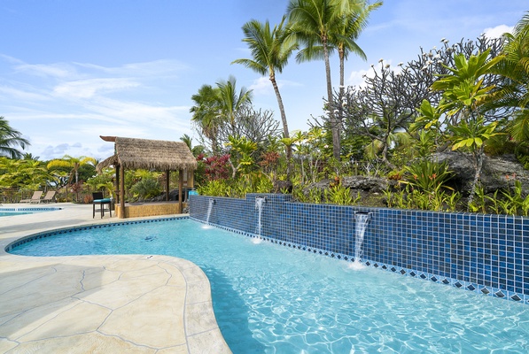 The pool is surrounded by palm trees and sun beds