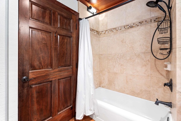 The primary bathroom featuring a tiled shower with elegant fixtures.