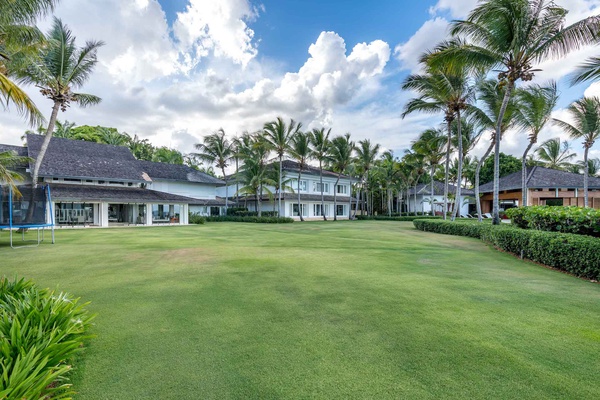 Expansive lawn area, ideal for outdoor activities, surrounded by lush tropical landscaping.