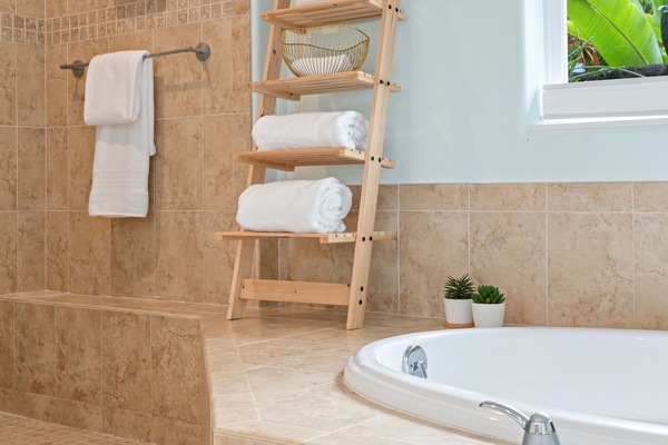 Ensuite with a luxurious bathtub beckons for a relaxing soak, accompanied by a small stool holding folded towels.