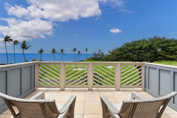 Relaxing bedroom lanai with scenic ocean and palm tree views.