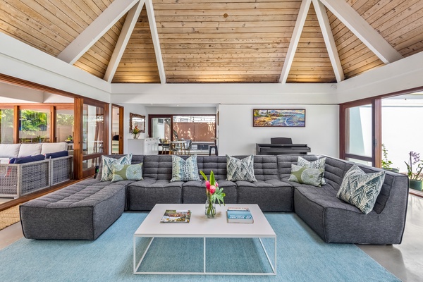 Experience the grandeur of a cathedral ceiling in the living area, complemented by a section of glass roofing, allowing an abundance of natural light to cascade in, illuminating the space beautifully.