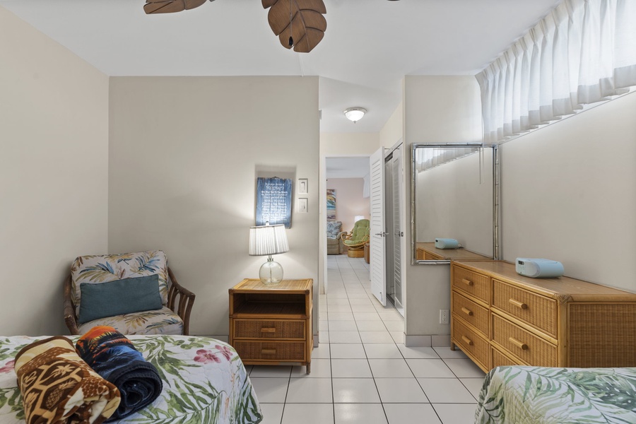 Tropical style guest bedroom with sitting nook and ceiling fan.