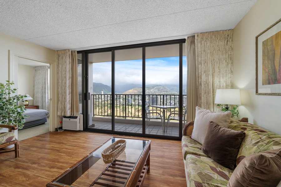 Spacious and sunlit living room, featuring comfortable seating and a stunning view of the Oahu skyline."