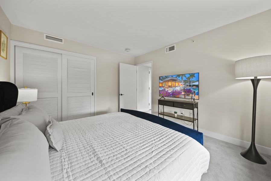 The guest bedroom has a flat-screen TV and a closet.